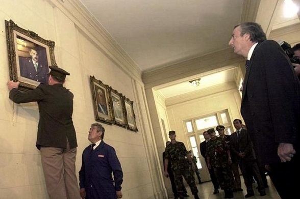 Néstor Kirchner descolgando el retrato de Videla de la galería presidencial. Militares lo permitieron