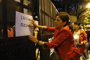 Woman holds a sign on a police fence during a protest over the death of prosecutor Alberto Nisman, in front of the Olivos presidential residence in Buenos Aires