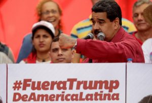 Venezuela's President Maduro stands next to a sign that reads "Trump go away from Latin America" gives a speech at a rally against U.S President Trump in Caracas